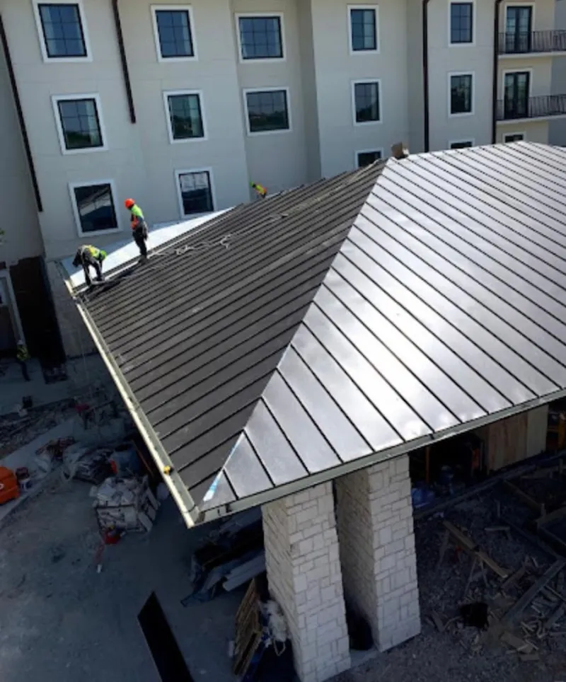 Crew installing standing seam metal roof panels on a commercial project in Emporia